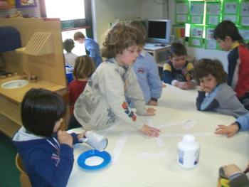 bambini che incollano strisce colorate sui barattoli per la costruzione dell'omino di latta