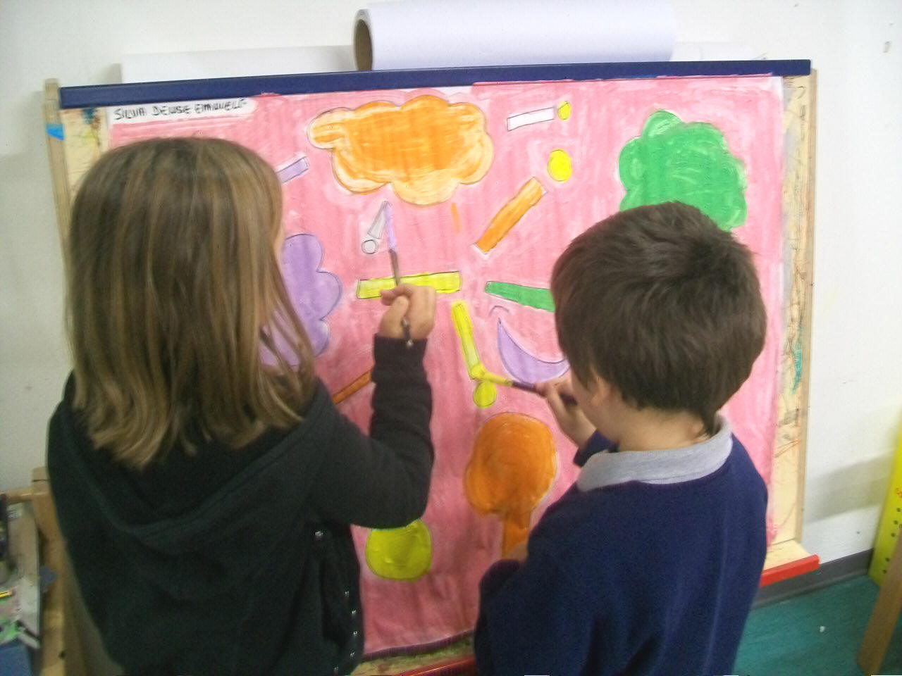 foto di bambini che pitturano un cartellone con i colori e le forme della felicit