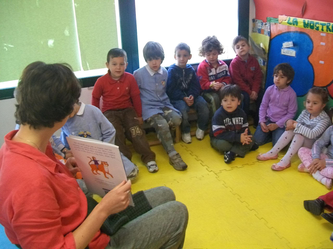 foto dell'insegnante che legge la storia  al gruppo di bambini