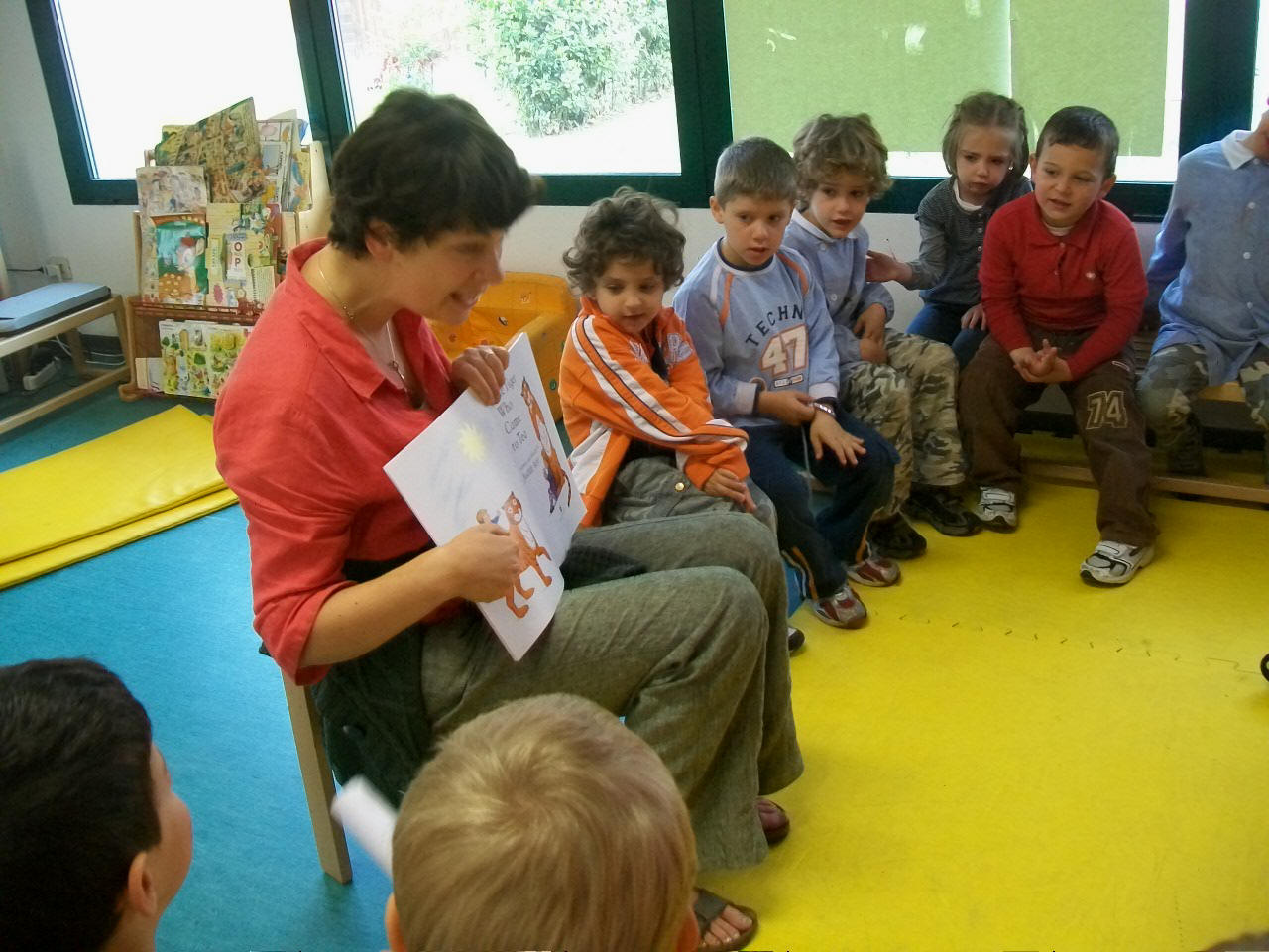 foto dell'insegnante che legge la storia  al gruppo di bambini