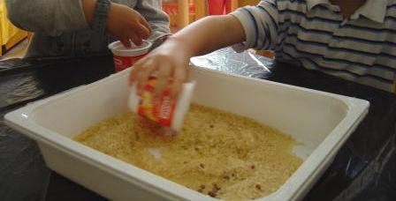 bambini che mettono il riso dentro ai barattolini