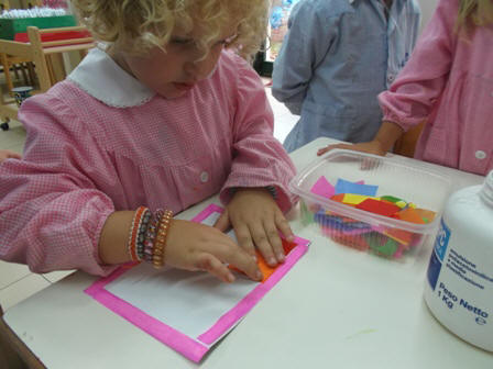 bambini che fanno collage con pezzettini di carta velina colorata per realizzare lo sfondo