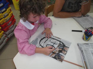 foto di bambini che disegnano con il carboncino su fogli di giornale