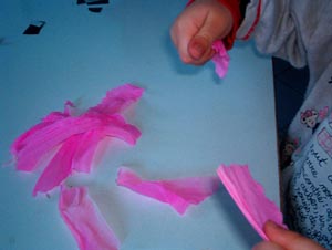 foto delle mani di un bambino che strappa la carta crespa