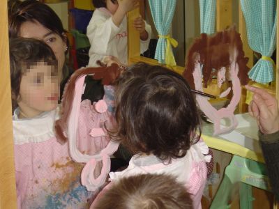 foto di una bambina che segue i contorni del suo viso con il pennello allo specchio